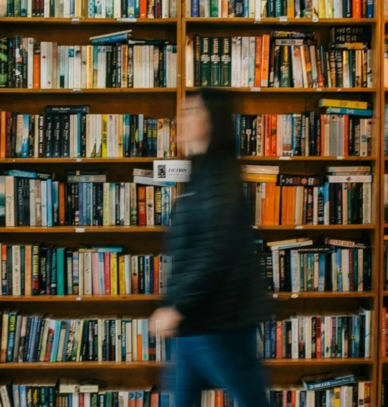 woman waking through bookstore in a blur with bookshelves behind her