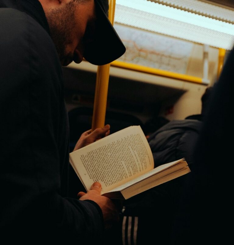 man reading book on subway while standing
