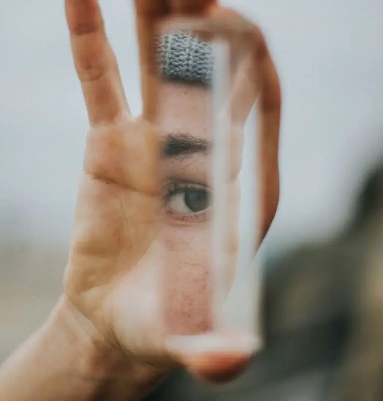 person self-reflecting while holding a mirror showing their reflected face