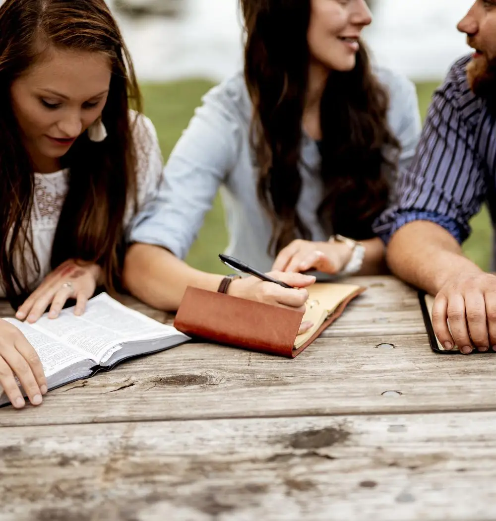 Group of young Christians read and take notes at picnic table