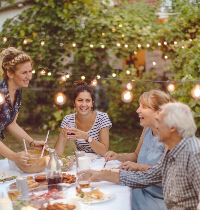 Intergenerational family talking and laughing at outdoor dinner table