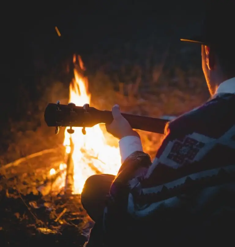 Christian man playing guitar by campfire as a hobby for Christian living