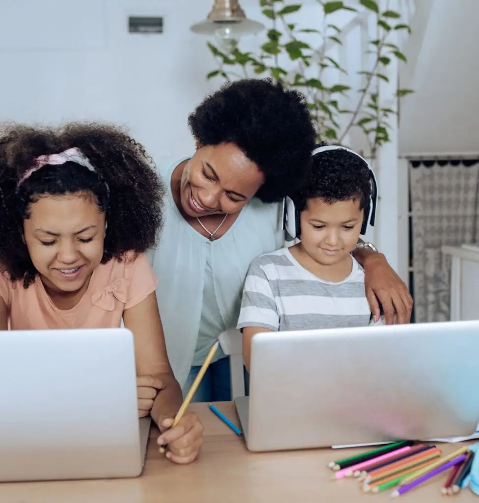 Christian family working on homeschool lesson at laptops