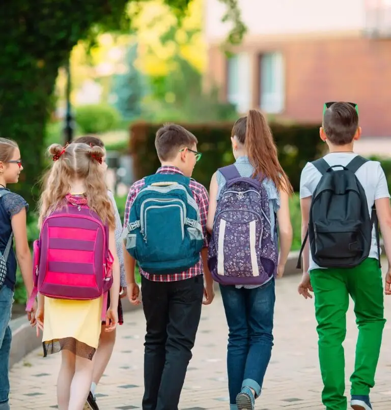 Young children wearing backpacks head back to school